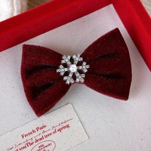 Détail d'une barrette à cheveux en velours rouge avec flocon de neige et perle centrée