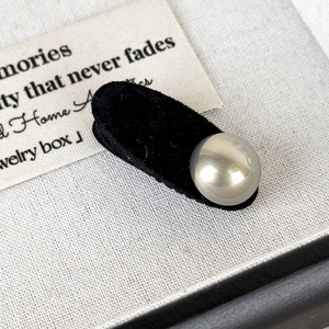 Close-up of a black velvet hair clip with a silver mirror-finish bead in a jewelry box