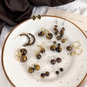Vintage tiger eye stone earring collection with gold and silver accents on white tray