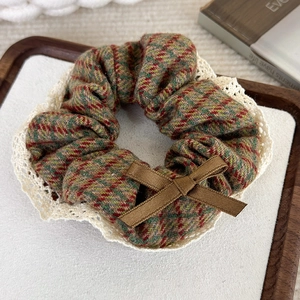 Détail d'un chouchou à carreaux avec bordure en dentelle blanche et un petit nœud marron