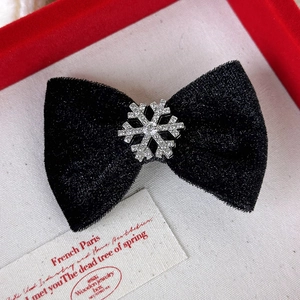 Détail macro d'un nœud en velours noir orné d'un flocon de neige étincelant en strass