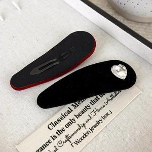 Dettaglio della molletta in velluto nero con strass a cuore e base in metallo