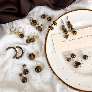 Vintage tiger eye earrings collection featuring round and geometric beads on white cloth