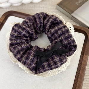 Détail du chouchou en tweed violet avec bordure en dentelle et petit noeud noir