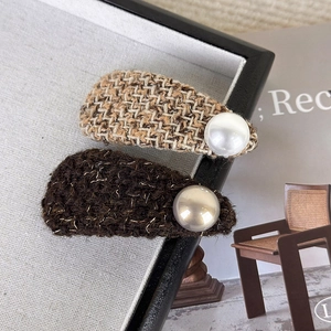 Close-up of brown tweed hair clips with pearl accents and vintage knitted texture