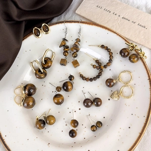 Close-up of tiger eye stone earrings with golden metal details displayed on a tray