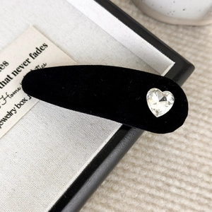 Dettaglio di un fermaglio vintage in velluto nero con strass a forma di cuore