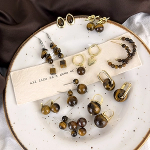 Vintage tiger eye stone earrings collection with golden finish on textured ceramic plate