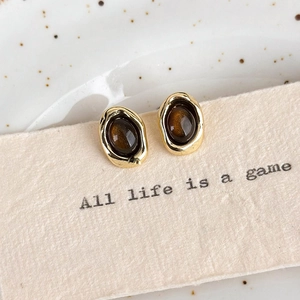 Detailed macro view of vintage gold irregular earrings with amber-like tiger eye stone