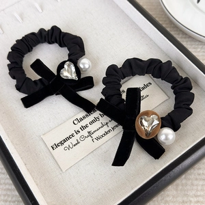 Close-up of velvet bow hair scrunchies with crystal heart and pearl detail on a tray