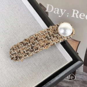 Detailed close-up of brown tweed knit hair clip with large round pearl accent
