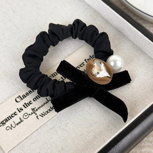 Close-up of velvet bow hair scrunchie with heart rhinestone and white faux pearl detail