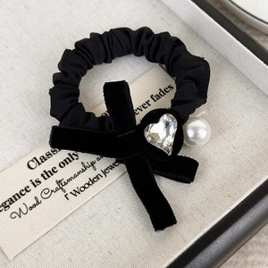 Detailed view of black velvet bow hair tie with heart rhinestone and faux pearl