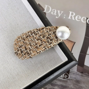 Close-up of brown tweed fabric hair clip with a large white pearl in elegant vintage style