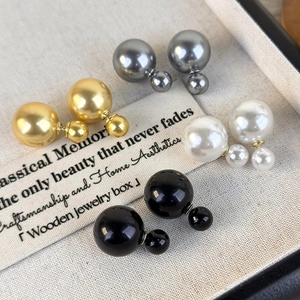 Close-up of four colors of double-sided pearl earrings in a beige jewelry display box