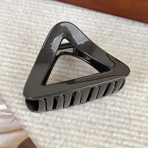Détail d'une grande pince à cheveux triangulaire noire brillante avec ressort en métal