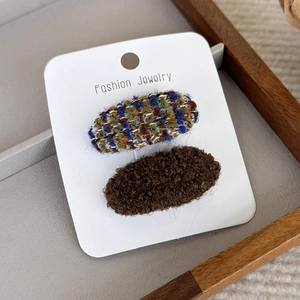 Détail de barrettes pour filles en tweed bleu et peluche marron sur support blanc