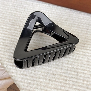 Détail d'une pince à cheveux triangulaire noire brillante sur fond en maille douce