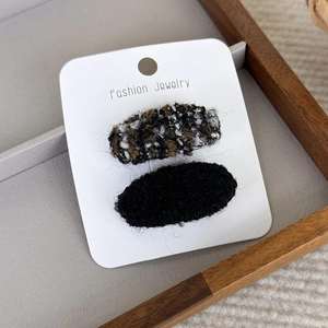 Détail de barrettes à cheveux en tweed et peluche noire sur carte de bijoux de mode