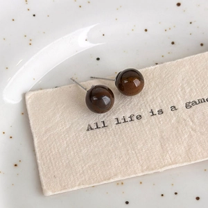 Detail macro shot of vintage round Tiger Eye stone stud earrings on aesthetic background