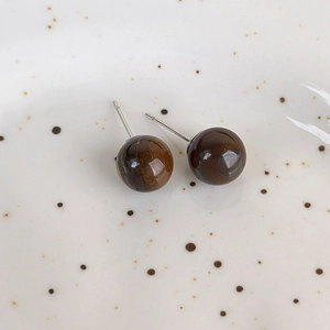 Macro shot of tiger eye bead earrings with natural textures on a ceramic plate