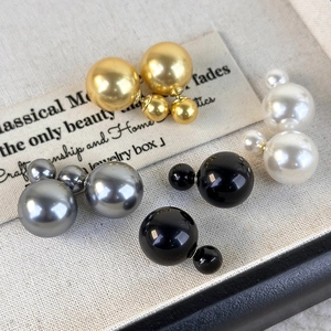 Detail of elegant double-sided pearl earrings in gold, white, grey and black colors