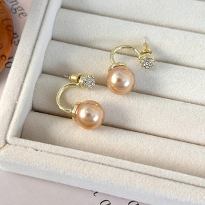 Elegant champagne gold pearl stud earrings with rhinestones on a grey velvet jewelry box