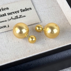 Detail of elegant gold double-bead earrings on a textured linen jewelry box background