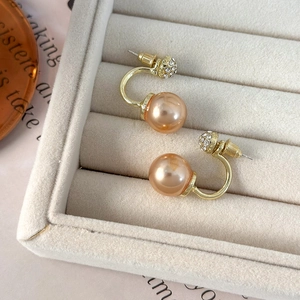 Macro detail of champagne pearl earrings with white rhinestones in a velvet jewelry box