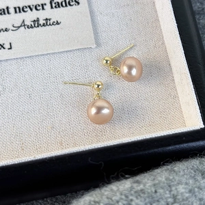 Detailed macro shot of vintage champagne pearl studs with golden needles on a tray
