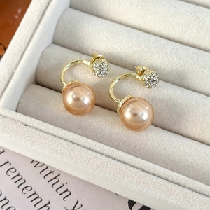 Macro view of champagne gold C-shape earrings with rhinestones and large pearls