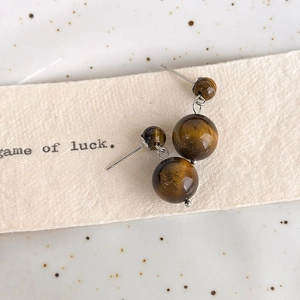 Close-up of vintage tiger eye stone earrings with silver hooks on decorative paper