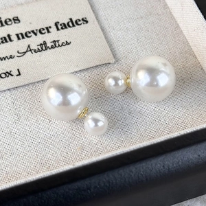 Macro shot of French style double-sided pearl earrings with elegant golden metal base