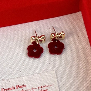 Macro view of gold bow and red flocked flower earrings in a vintage velvet jewelry box