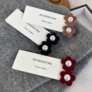 Detail view of handmade velvet flower hair clips with central pearl in autumn colors