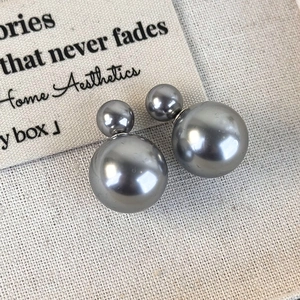 Close-up of elegant double-sided grey pearl earrings on textured fabric background