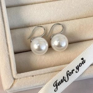 Primer plano de elegantes pendientes de perlas blancas de 10mm en un joyero de terciopelo