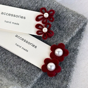Close-up of red velvet flower hair clips with white pearls on a display card