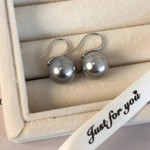 Elegantes pendientes de perlas grises con ganchos de plata en una caja de regalo de terciopelo