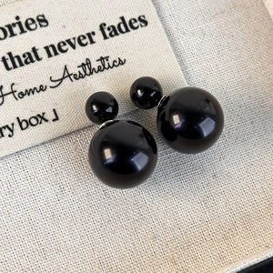 Macro shot of glossy black double pearl earrings with high-shine polished finish