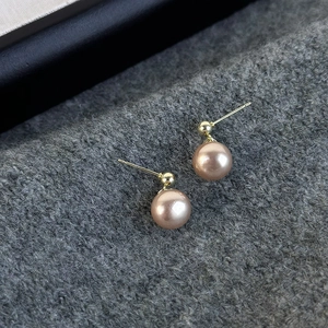 Elegant champagne pearl stud earrings on gray knitted background with vintage gold finish