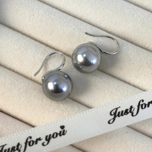 Detalle de pendientes de perlas gris plateado sobre una caja de regalo de terciopelo