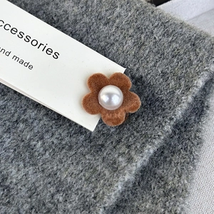 Detail of velvet flower hair clip with white pearl center on brown flocked petals