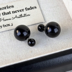 Close-up of elegant double-sided black pearl earrings in a luxury jewelry display box