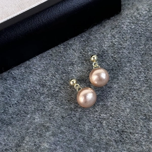 Elegant champagne pearl stud earrings on cozy grey knit fabric for a vintage look