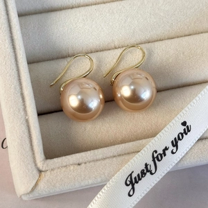 Detalle de elegantes pendientes de perlas champán con ganchos dorados en un joyero