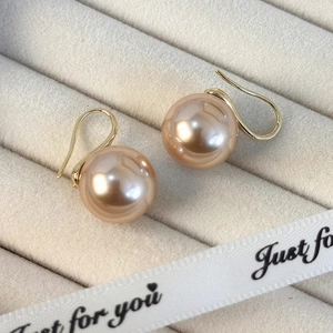 Detalle de pendientes de perlas redondas champán con acabado dorado sobre terciopelo