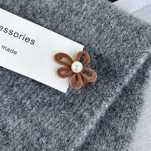Detailed macro view of a brown velvet flower hair clip with a center pearl detail