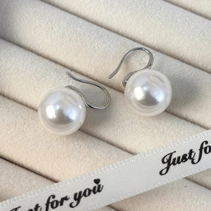 Primer plano de aretes de perlas blancas en una bandeja de joyería de terciopelo beige