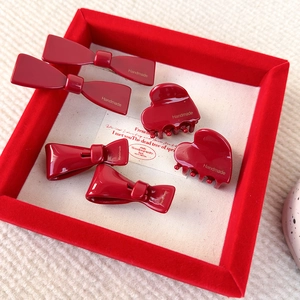 Pinzas para el pelo con lazo rojo de acetato y garras de corazón en bandeja de terciopelo